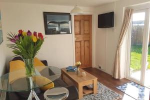 a living room with a glass table and a vase of flowers at The Garden Room in Chichester