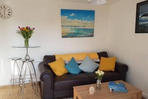 a living room with a couch with yellow and blue pillows at The Garden Room in Chichester