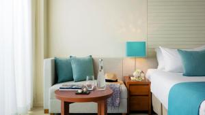 a bedroom with a bed and a table and a chair at ANA InterContinental Manza Beach Resort by IHG in Onna