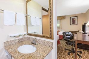a bathroom with a sink and a mirror in a hotel room at Days Inn & Suites by Wyndham Madison Heights MI in Madison Heights