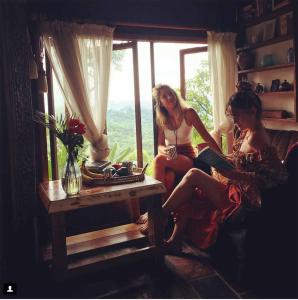 zwei Frauen sitzen in einem Zimmer mit Fenster in der Unterkunft The Den of the Treehouse, KINABALU Farm in The Pocket