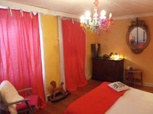 a bedroom with red curtains and a bed and a chair at La chambre rose in Rosenwiller