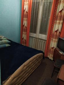 a bedroom with a bed and a window and a television at Готель Турист in Mohyliv-Podilʼsʼkyy
