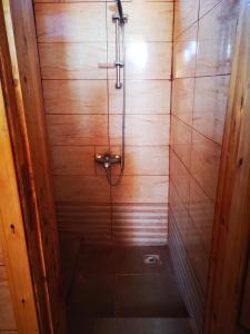 La salle de bains est pourvue d'une douche et d'un mur en bois. dans l'établissement Beyond Wadi Rum Camp, à Wadi Rum