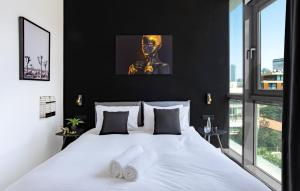 una camera da letto con un letto bianco e pareti nere di High Standing at Hayarkon by HolyGuest a Tel Aviv