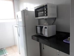 a kitchen with a microwave and a refrigerator at Condominio dos Lagos Capitolio 01 in Capitólio