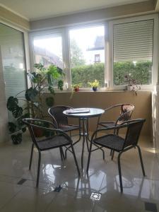 einen Tisch und Stühle in einem Zimmer mit Fenstern in der Unterkunft Noémi Wellness Apartman in Siófok