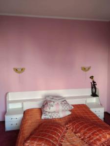 Schlafzimmer mit rosa Wänden und einem Bett mit Kissen in der Unterkunft Готель Турист in Mohyliv-Podilʼsʼkyy