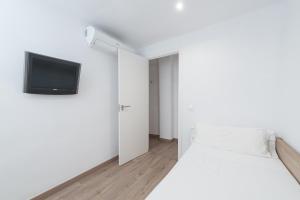 a white bedroom with a bed and a tv on the wall at Centric in Palma de Mallorca