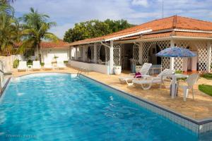 a swimming pool with chairs and an umbrella next to a house at Recanto Serenissima in São Pedro
