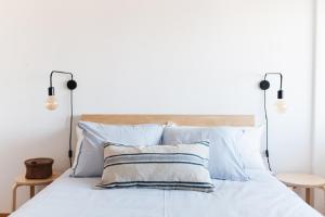 Dormitorio blanco con cama con almohadas azules en Cozy Panoramic Apartment near Metro Station, en Senhora da Hora