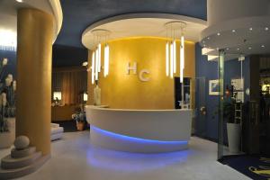 a lobby with a yellow wall and chandeliers at Hotel Corallo in Bibione