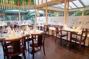 a restaurant with wooden tables and chairs and windows at Amrâth Hotel Lapershoek Arenapark in Hilversum