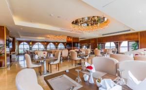 فندق واحة جدة في جدة: مطعم فيه كراسي بيضاء وطاولات ونوافذ