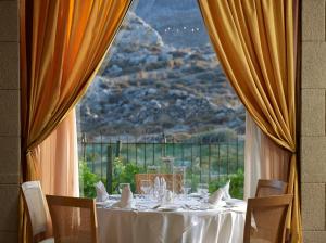 
a dining room table with a large window at Mitsis Lindos Memories Resort & Spa in Líndos
