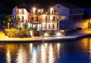 a large house with lights on the water at night at Apartments Malo Lago in Lastovo