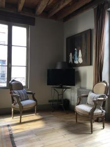 een woonkamer met 2 stoelen en een flatscreen-tv bij Maison Joséphine avec garage privé in Blois