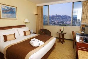 ein Hotelzimmer mit einem Bett und einem großen Fenster in der Unterkunft Carlton Madagascar in Antananarivo