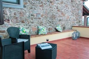 une terrasse avec des chaises et un banc avec un verre de vin dans l'établissement Agriturismo Il Cuscino Nel Pagliaio, à Campiglia Marittima