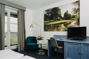 a hotel room with a desk with a television and a golf course at Gutshof Sagmühle in Bad Griesbach