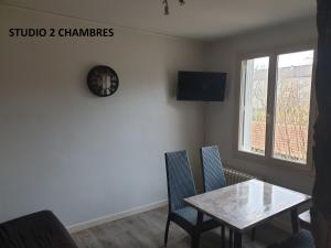 a dining room with a table and chairs and a clock at Chez les chtis de vayrac in Vayrac