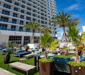 un patio avec des chaises et des palmiers ainsi qu'un grand bâtiment dans l'établissement HYDE Beach House Apartments, à Hollywood