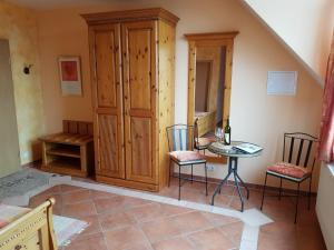 a room with a cabinet and two chairs and a table at Weingut und Gästehaus Henrici in Friesenheim