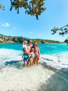 una famiglia in piedi sull'acqua sulla spiaggia di Cape Santa Maria Beach Resort & Villas a Seymourʼs