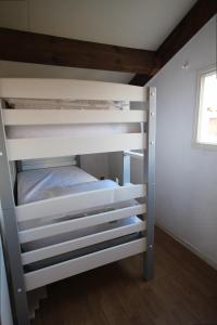 ein weißes Etagenbett in einem Zimmer mit Fenster in der Unterkunft Maison T2 cabine 4 couchages, terrasse clôturée -résidence Sun village avec piscine commune, 300m de la plage à PORTIRAGNES LRSUNO5 in Portiragnes