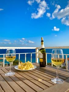 two glasses of wine and a plate of grapes on a deck at Villa Veli Nova in Zavala