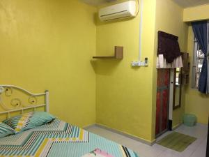 a bedroom with a bed and a yellow wall at Pandan Home Stay in Alor Setar