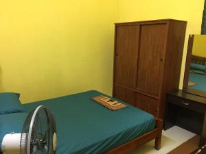 a bedroom with a bed with a fan and a cabinet at Pandan Home Stay in Alor Setar