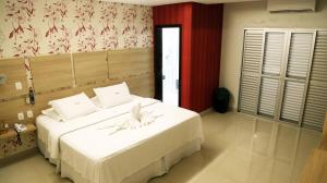 a bedroom with a large white bed with a flower on it at Tezla Hotel in Primavera do Leste +212 photos