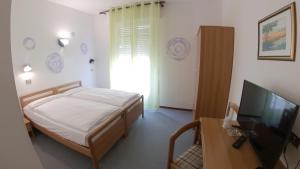 Schlafzimmer mit einem Bett und einem Flachbild-TV in der Unterkunft Hotel Alberello in Riva del Garda