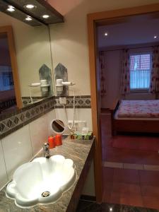 a bathroom with a sink and a bedroom with a bed at Weingut und Gästehaus Henrici in Friesenheim