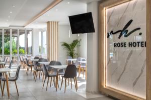 um restaurante com mesas e cadeiras e uma televisão na parede em Rose Hotel Faliraki em Faliraki