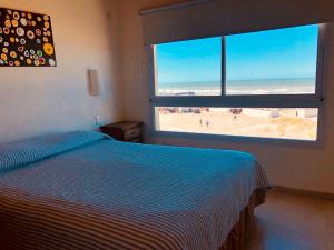 a bedroom with a bed and a large window with a beach at Namaste casas de mar in Villa Gesell +56 photos