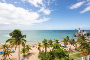 uma vista para uma praia com palmeiras e para o oceano em ESJ Towers by Chana em San Juan
