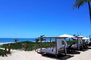 eine Gruppe von Stühlen und Sonnenschirmen am Strand in der Unterkunft Hotel e Resort Villas de Trancoso in Trancoso