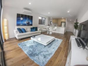 a living room with a white couch and a blue rug at 1 Bdrm Close Airport/Shops, WIFI, NETFLIX, PARKING in Perth