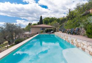 a swimming pool with a stone wall and a house at Les Mas d'Azur Appartement in Vence