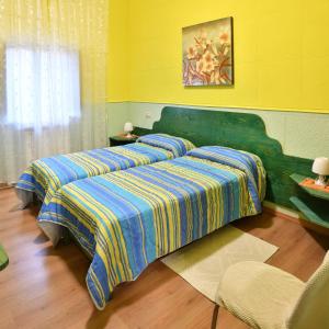 two beds in a room with yellow walls at B&B Mitzixeddas Sa Domu de Braxia in Màndas