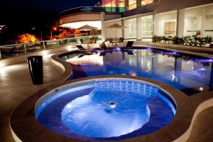 a large swimming pool in a hotel at night at Premier Parc Hotel in Juiz de Fora