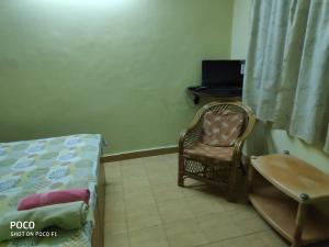 a bedroom with a chair and a desk with a laptop at Hidden heart guest house in Candolim