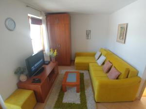 a living room with a yellow couch and a tv at Apartment Panorama 1 in Vlasic
