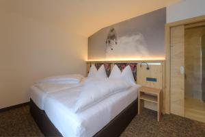 sypialnia z dużym białym łóżkiem i prysznicem w obiekcie Arula GmbH w mieście Sankt Anton am Arlberg
