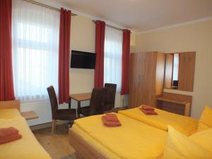 a hotel room with two beds and a table and chairs at Pension am Elberadweg in Radebeul