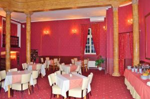 a restaurant with red walls and tables and chairs at Hotel Petr in Karlovy Vary