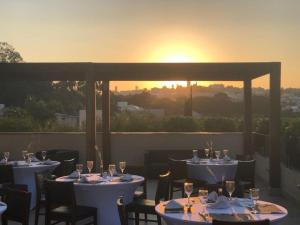 ein Restaurant mit Tischen und Blick auf den Sonnenuntergang im Hintergrund in der Unterkunft Blue Tree Towers Valinhos in Valinhos
