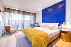 a bedroom with a large bed with a blue wall at Praia do Sal Resort & SPA in Alcochete